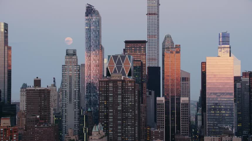 City skyline at dawn with moon setting in background