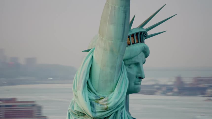The statue of liberty is in the water by the city