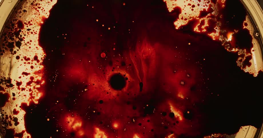 Red colored ink spread out over a gold object