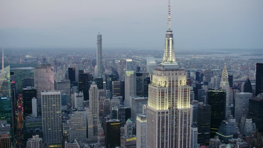 The empire state building and city skyscrapers glow at dusk