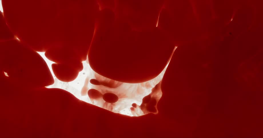 An abstract shot of a red dye blending in to a clear liquid