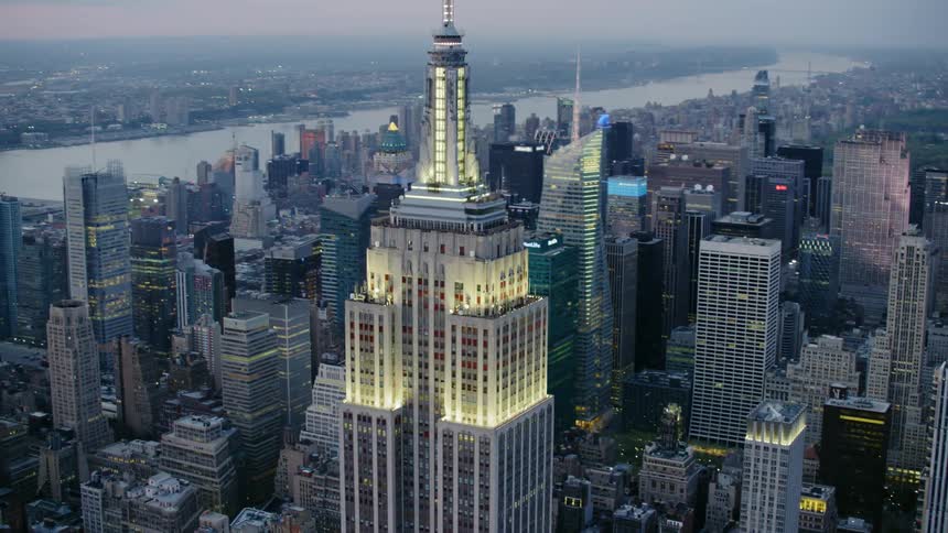 The empire state building and city glow at dusk