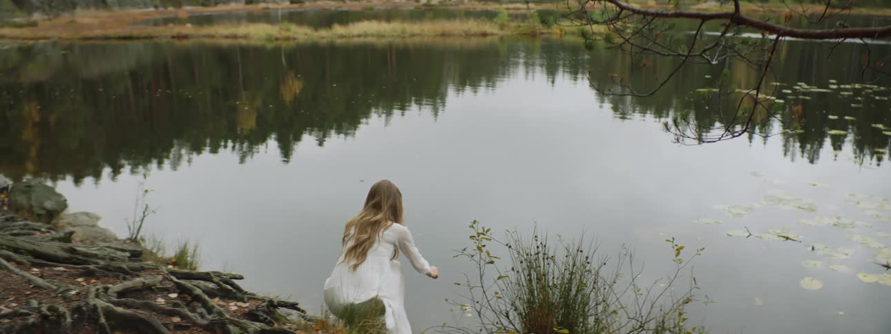 A woman wearing a dress is outdoors in a nature area