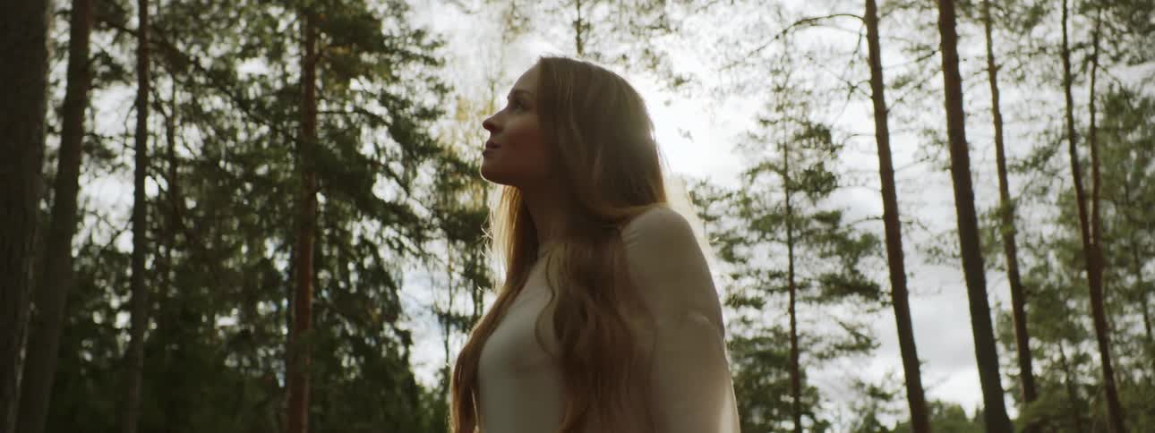 Sunlight shines on a woman standing in a sunny forest