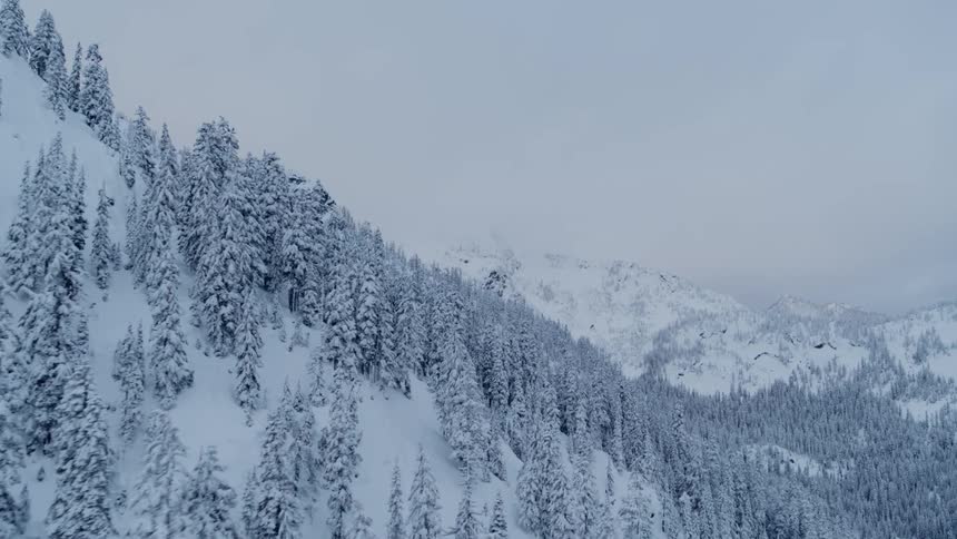 Flying close along a steep slope to reveal distant mountaintops