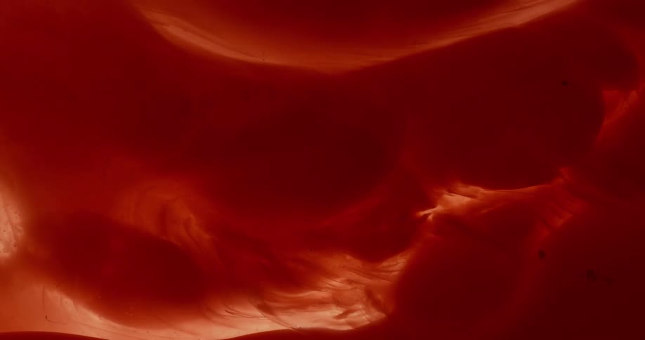 Blobs of reddish fluid stream and mix together
