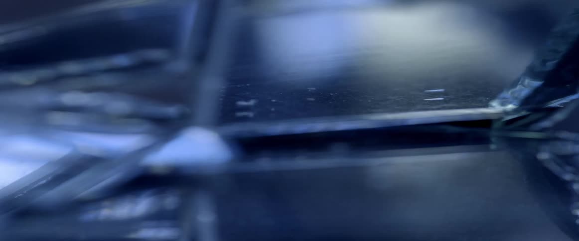 A bluish light shines and glows on glass surface and edge