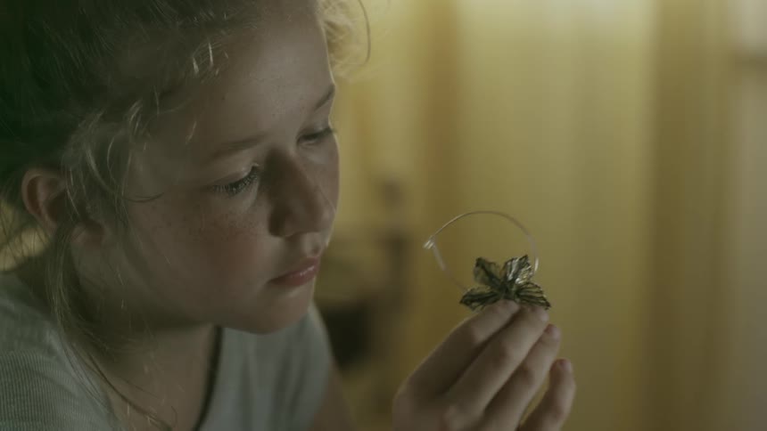 A girl is flipping an item in her fingers while looking at it