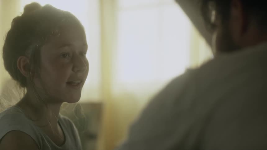 A girl in a white shirt smiles and talks with another person