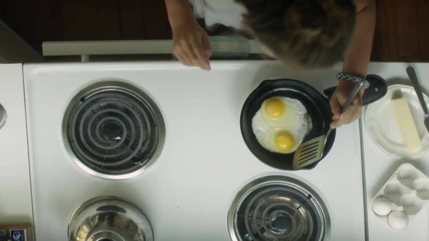 A woman is cooking some eggs on a stove