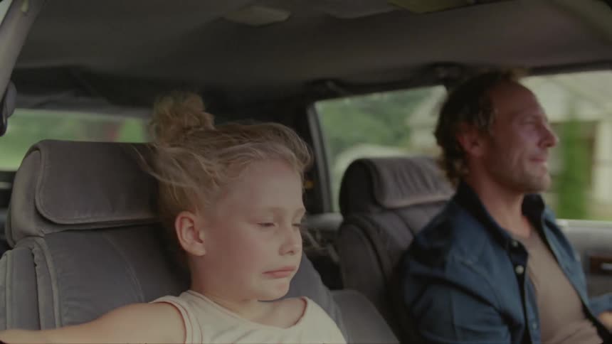 A man and girl are sitting in a car traveling