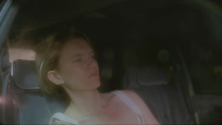 A woman is sitting in a vehicle with her head on on her hand
