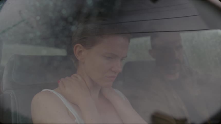 A man driving a car talks to a woman in the passenger seat