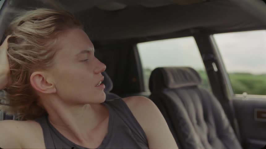 A woman sitting in a moving car speaking