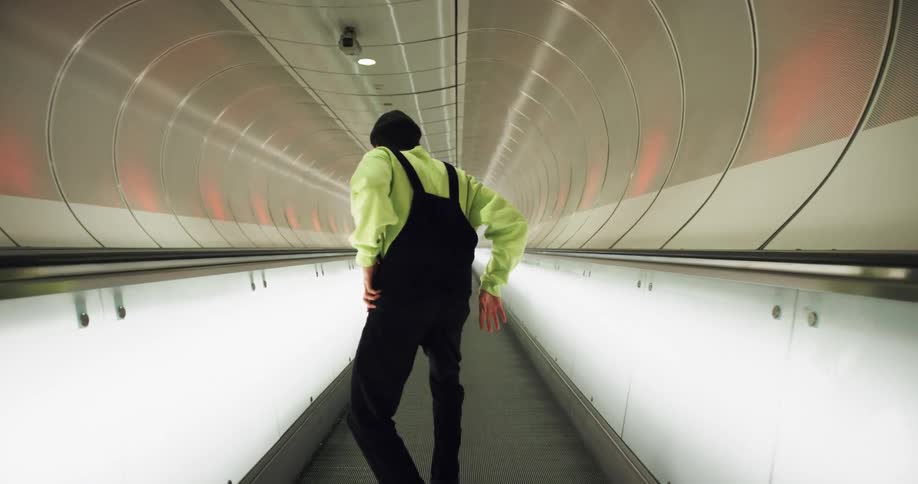 A teenager dances on an auto walkway at an airport