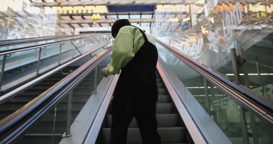 A person dances as they ride an escalator