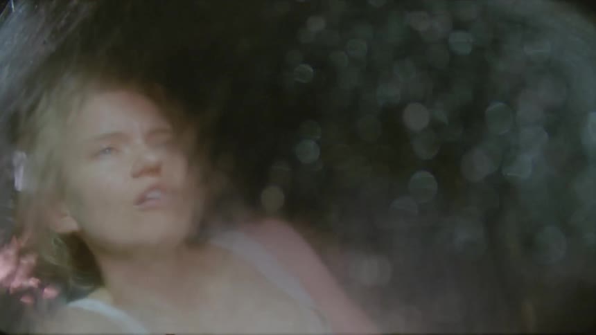 View of a woman through a window as rain washes down the glass