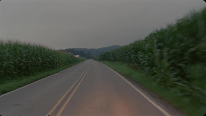A vehicle drives down a rural road