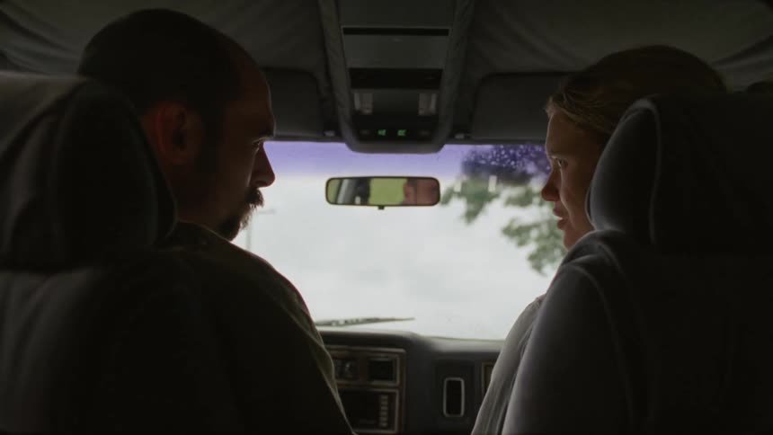 Two people are traveling in a vehicle and talking