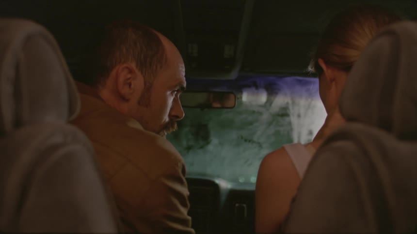 A man and woman sitting in a vehicle and talking