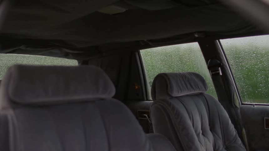 Inside of a vehicle as wind ruffles the roof fabric on a rainy day