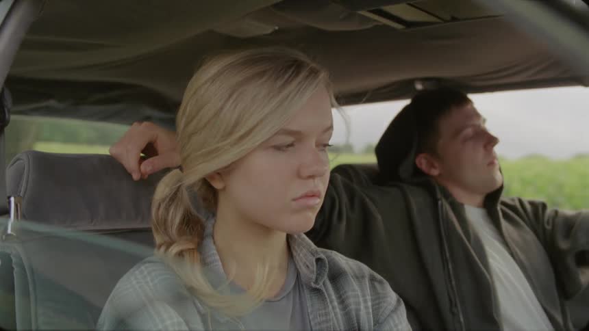 A man and woman are driving in a car the man puts his arm on her seat