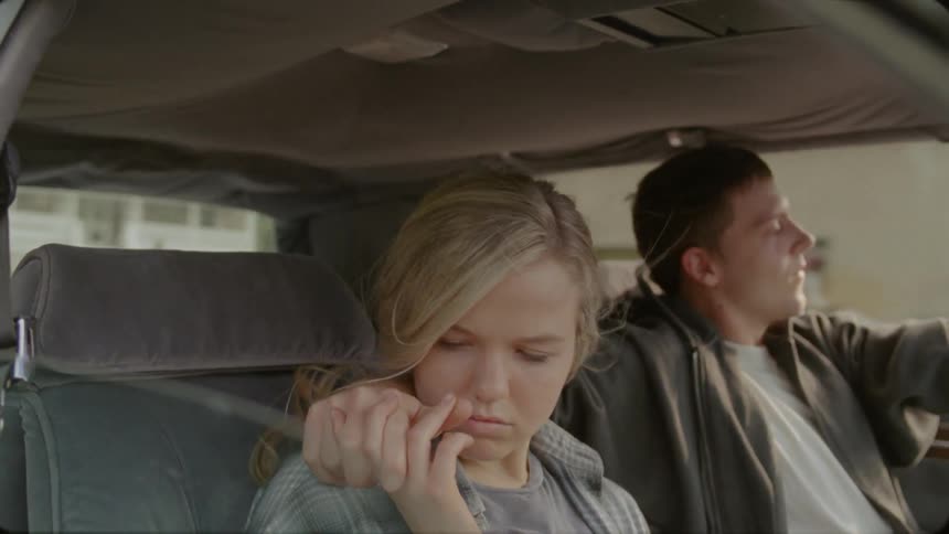 A man puts his arm around a woman's shoulder in a vehicle