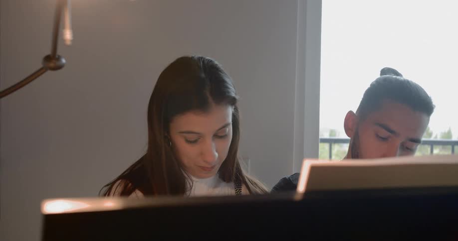 A man and woman sit at a piano together