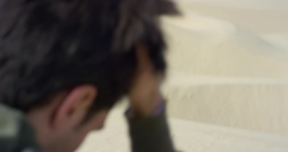 A man wipes his forehead in the desert