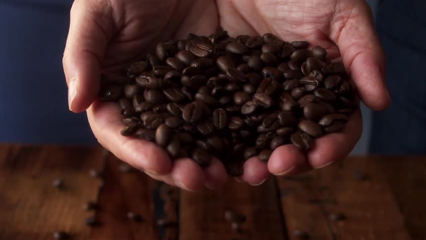 Coffee beans being poured in to a mans hand