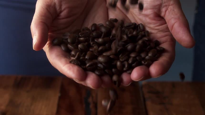 Coffee beans falling into a persons cupped hands