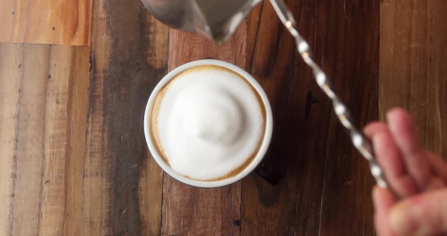 A person with a spoon adding foam to a drink