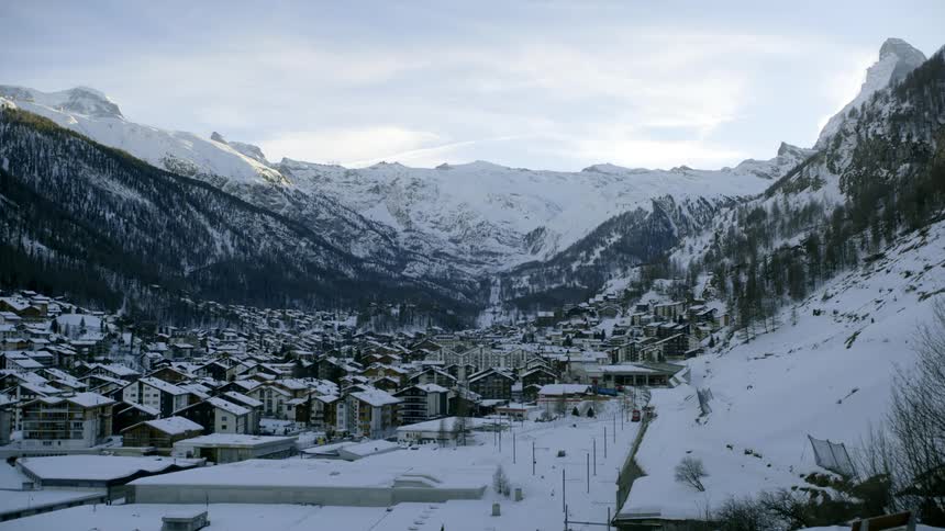 A town in a mountain valley with mountains in the background