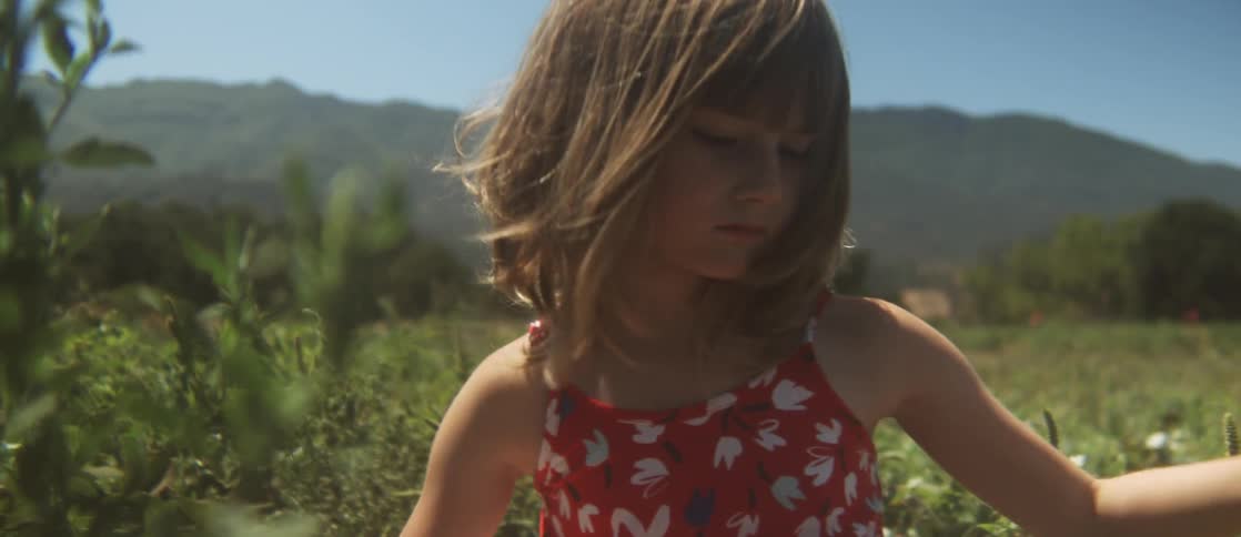 A young girl rubbing her arms before she picks fruit in a berry patch