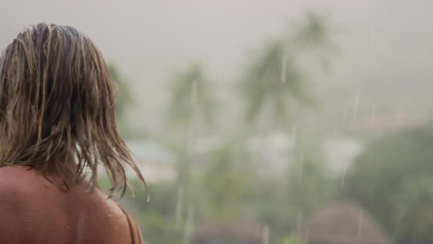 A woman in her bathing suit walks outside in the rain