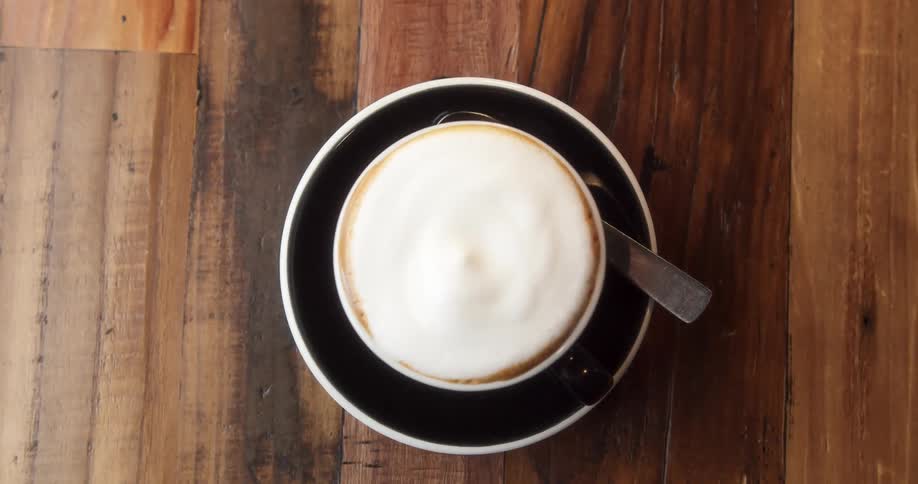 Person places spoon on the plate under a coffee cup