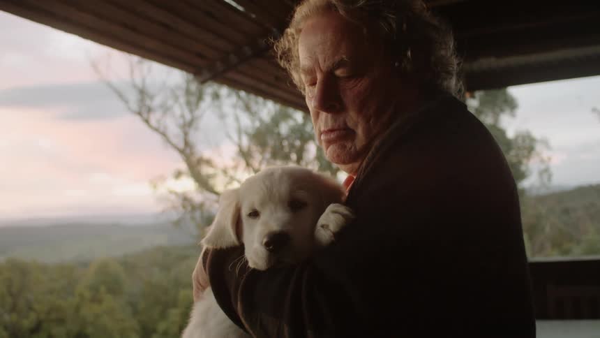 A man holding a puppy and kissing it