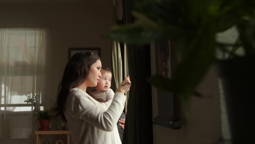 Mother talks to his baby near a window on her home