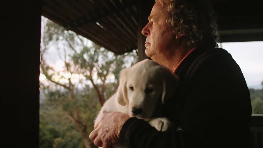Older adult holding a puppy in the proch at sunset