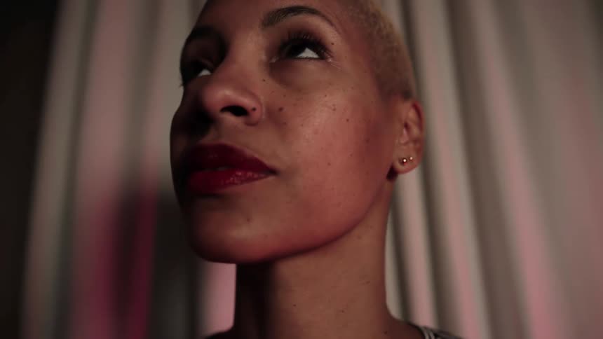 A black woman stands in a room and looks around
