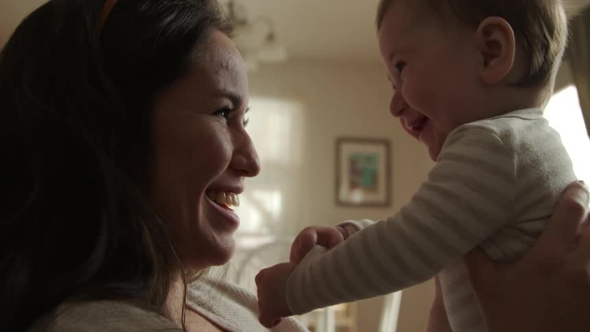 A mother holds her baby and they laugh together