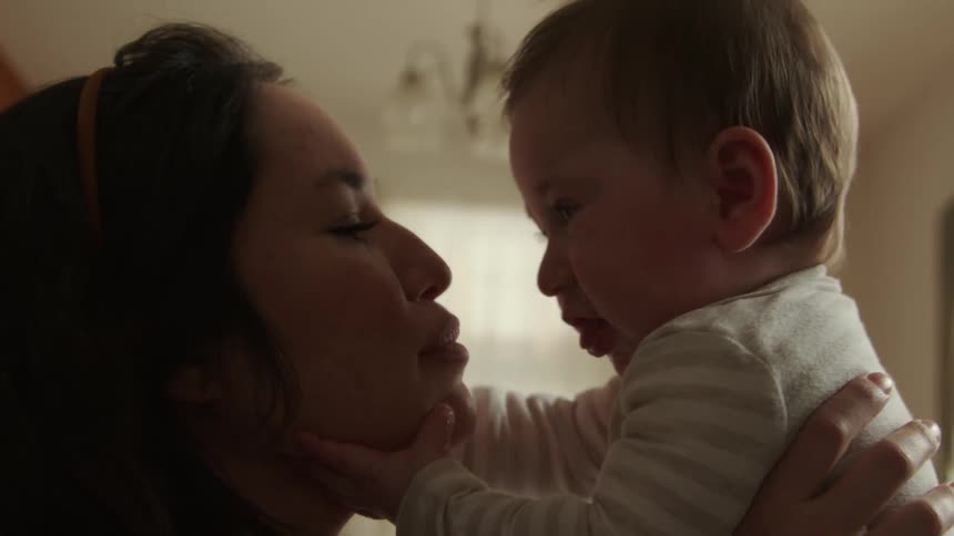 A mother and her infant sit in a room and play together