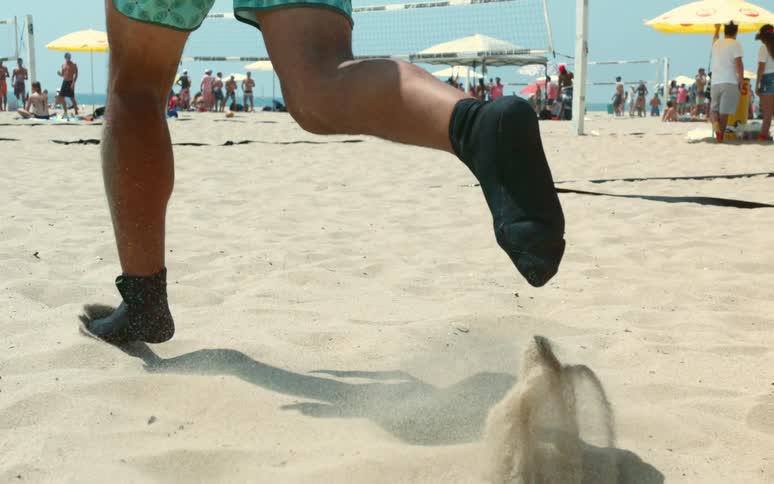 A man runs across a beach in black footwear