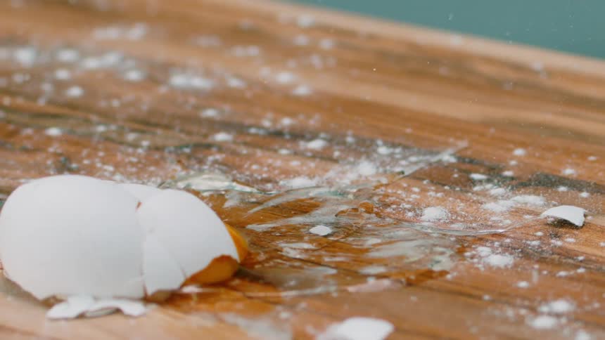 An egg is dropped on the table and breaks