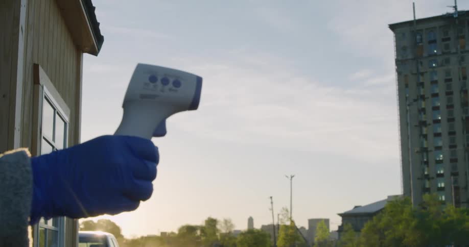 A person holding a thermometer reaches to take a temperature