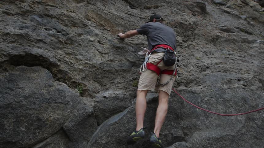A man in a harness climbing a rock face