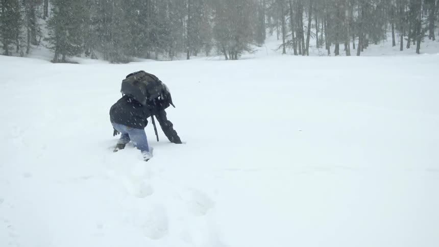 A man climbs and crawls through the snow