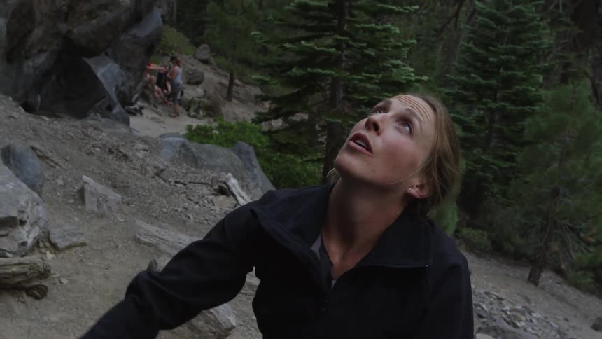 Woman prepares rope for rock climbing near forest