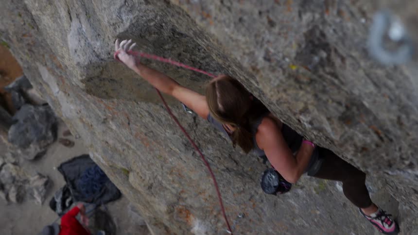 A woman ties her rope in as she rock climbs