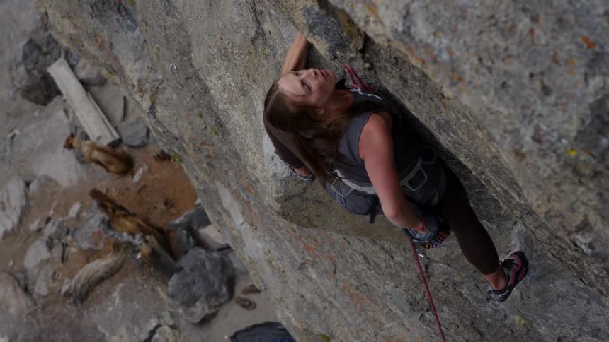 A woman reaches for her chalk bag while rock climbing